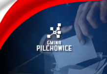 Grafika - wybory - kartka wrzucana do urny wyborczej + logo gminy + wstęga biało-czerwona
